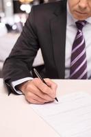 assinatura de um contrato. close-up de homem maduro em traje formal, assinando um documento foto