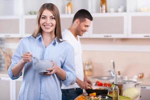 cozinhando o café da manhã juntos. casal feliz cozinhando juntos na cozinha enquanto mulher olhando para a câmera e sorrindo