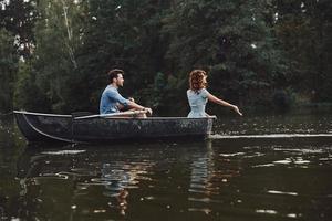 jovem e livre. lindo casal jovem desfrutando de um encontro romântico enquanto remava um barco foto