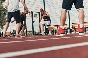 vencedores nunca desistem. grupo de jovens em roupas esportivas jogando basquete enquanto passa o tempo ao ar livre foto