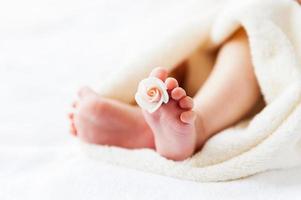 pés minúsculos. close-up de pés de bebê com flor deitada na cama foto
