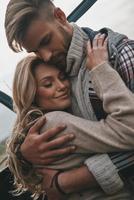 lindo casal jovem abraçando e sorrindo em pé ao ar livre foto