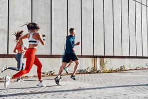 comprimento total de jovens em roupas esportivas correndo enquanto se exercitam na calçada ao ar livre foto