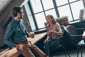 dois colegas modernos em roupas casuais inteligentes discutindo algo enquanto trabalhava no escritório foto