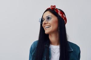 moda jovem em bandana sorrindo em pé contra um fundo cinza foto