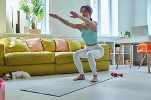 jovem confiante em roupas esportivas se exercitando em casa foto