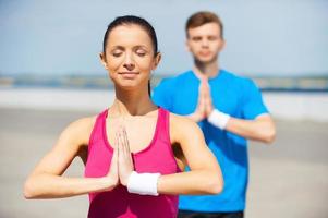 meditando juntos. jovem e homem meditando juntos em pé ao ar livre foto