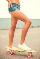 pronto para se divertir. close-up de mulher jovem e bonita com nádegas perfeitas andando de skate foto