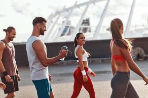 grupo de jovens em roupas esportivas caminhando enquanto relaxa após o exercício ao ar livre foto