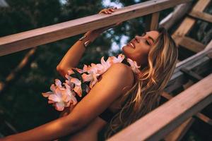 linda em qualquer coisa. mulher jovem e atraente vestindo lei havaiana e sorrindo enquanto está sentado nos degraus de madeira foto