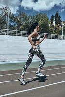 treino matinal. comprimento total de jovem em roupas esportivas correndo enquanto se exercita ao ar livre foto