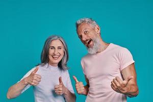 lindo casal sênior olhando para a câmera e mantendo os polegares para cima foto