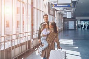 pai feliz com a filha encontrando a esposa no terminal do aeroporto foto