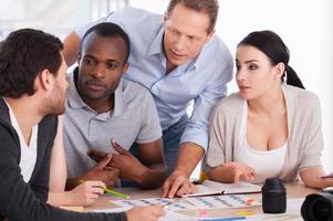 discussão de escritório quente. grupo de empresários alegres sentados juntos à mesa e discutindo algo foto