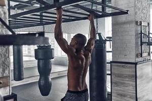 jovem e cheio de energia. jovem africano sem camisa fazendo flexões durante o exercício no ginásio foto