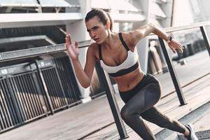 mulher jovem e bonita em roupas esportivas correndo enquanto se exercita ao ar livre foto