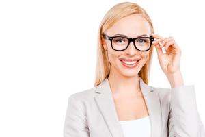 bonito e inteligente. empresária madura confiante ajustando seus óculos e sorrindo em pé contra um fundo branco foto