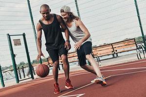 dois jovens em roupas esportivas jogando basquete e sorrindo enquanto passam o tempo ao ar livre foto