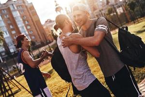 amigos para sempre. grupo de jovens em roupas esportivas, gesticulando e sorrindo em pé ao ar livre foto