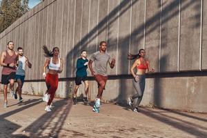 comprimento total de pessoas em roupas esportivas correndo enquanto se exercita na calçada ao ar livre foto