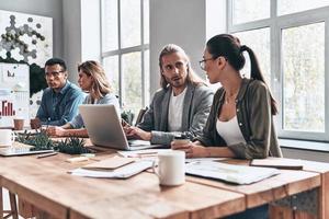 entendimento mútuo. grupo de jovens modernos em roupas casuais inteligentes discutindo negócios enquanto trabalhava no escritório criativo foto