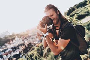 capturando cada momento. jovem em roupas casuais fotografando a vista em pé na colina ao ar livre foto