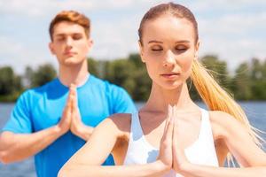 meditando juntos. jovem e homem meditando juntos em pé ao ar livre foto