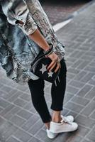 garota na moda. close-up vista traseira do jovem carregando uma bolsa enquanto caminhava na rua foto