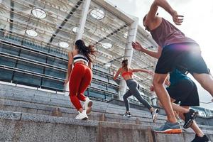 grupo de jovens em roupas esportivas correndo enquanto se exercita nas escadas ao ar livre foto