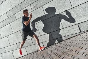 esporte é o modo de vida. comprimento total de jovem em roupas esportivas correndo durante o exercício fora foto