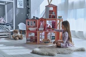 sentindo brincalhão. menina bonitinha brincando com uma casa de bonecas enquanto está sentado no chão no quarto foto