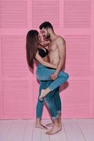 beleza e estilo. comprimento total do belo casal jovem, cara a cara, em pé contra um fundo rosa foto