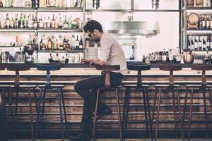 empresário cansado no bar. jovem frustrado em roupas casuais inteligentes, sentado no balcão do bar foto