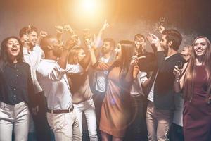 comemorando a noite toda. grupo de jovens bonitos dançando juntos e parecendo felizes foto