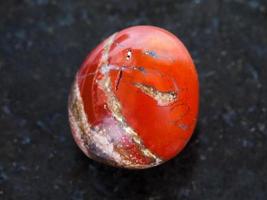 pedra preciosa de jaspe vermelho polido em fundo escuro foto
