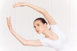 movendo-se com graça. confiante jovem bailarina em tutu branco dançando no estúdio de balé foto