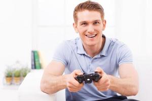 homem jogando videogame. jovem feliz usando joystick enquanto joga videogame em casa foto