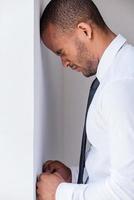 empresário deprimido. vista lateral do jovem deprimido de camisa e gravata, encostado na parede e mantendo os olhos fechados foto