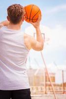 jogar basquete. vista traseira do jovem jogador de basquete masculino pronto para o tiro foto