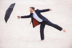 cavalheiro com guarda-chuva. jovem brincalhão em trajes formais segurando guarda-chuva em pé no deserto foto