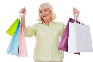 eu amo fazer compras mulher sênior feliz esticando as mãos com sacolas de compras e sorrindo em pé isolado no fundo branco foto