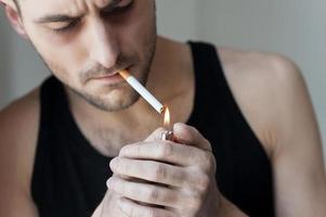 eu preciso de mais um cigarro. close-up de jovem acendendo um cigarro foto