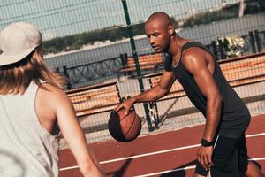 esporte é o modo de vida. dois jovens em roupas esportivas jogando basquete enquanto passam tempo ao ar livre foto