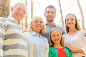 tempo para a família. vista de ângulo baixo da família feliz de cinco pessoas, unindo-se e sorrindo ao ar livre juntos foto