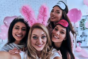 selfie perfeita. autorretrato de quatro jovens brincalhões sorrindo e olhando para a câmera enquanto faz uma festa do pijama foto