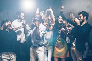 eles só querem se divertir. grupo de jovens bonitos dançando juntos e parecendo felizes foto