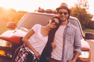 pronto para viagem. lindo jovem casal sorridente, unindo-se e inclinando-se em sua caminhonete foto