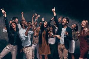 curtindo festa incrível. grupo de jovens bonitos dançando com taças de champanhe e parecendo feliz foto