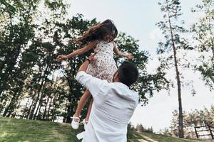 ficando loucos juntos. jovem pai amoroso carregando sua filha sorridente enquanto passa o tempo livre ao ar livre foto