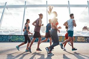 comprimento total de jovens em roupas esportivas correndo ao ar livre foto